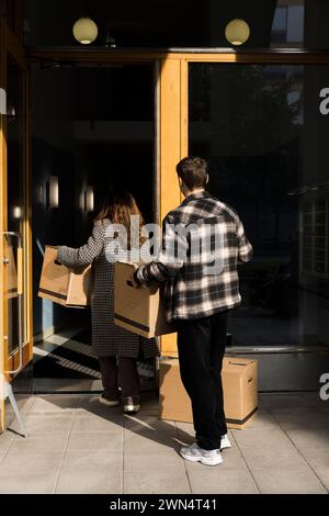 Multiracial couple carrying boxes while walking in apartment building Stock Photo