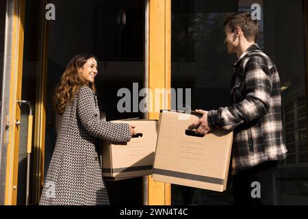Multiracial couple assisting each other while carrying boxes during relocation of house Stock Photo