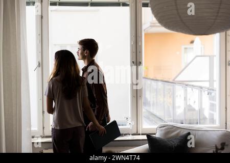 Multiracial couple looking through window while standing at new home Stock Photo