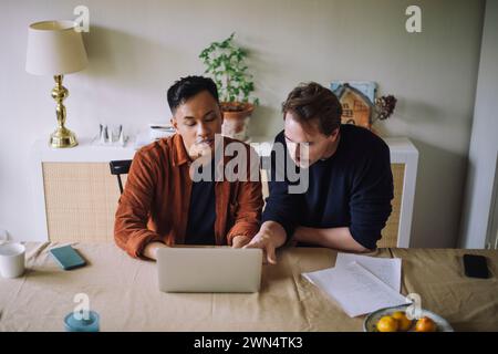High angle view of gay couple discussing over laptop while working from home Stock Photo