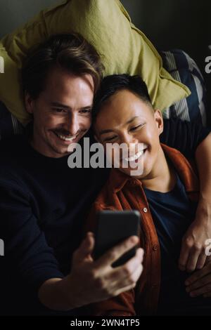 High angle view of smiling gay couple using smart phone at home Stock Photo