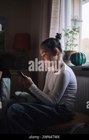 Girl using smart phone while sitting at home Stock Photo