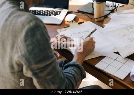 Midsection of male architect drawing blueprint on paper at desk in home office Stock Photo