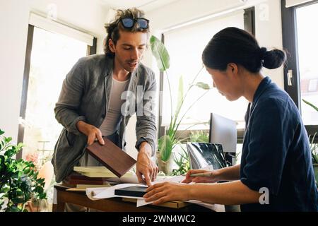 Male and female architects deciding on wooden plank at home office Stock Photo