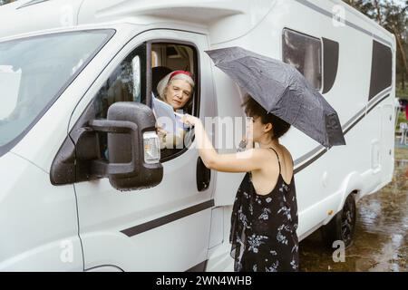 Young woman with umbrella helping senior woman for direction Stock Photo