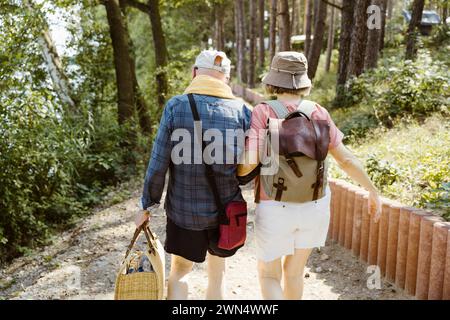 Rear view of retired senior couple walking together while hiking in forest Stock Photo