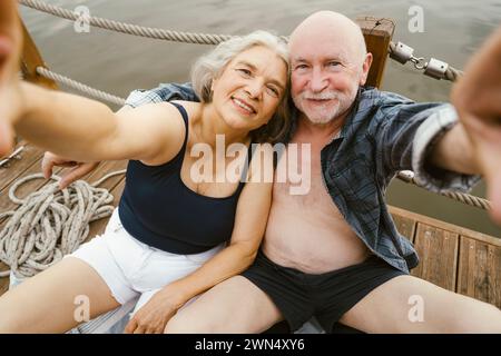 Happy senior couple taking selfie while sitting on houseboat Stock Photo