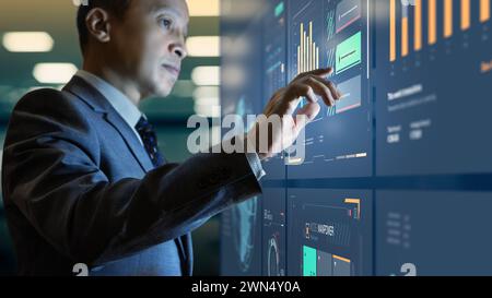 Asian businessman interacting with modern business information dashboard analysing a return on investment Stock Photo