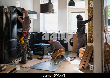 Diverse male and female carpenters working in kitchen at site Stock Photo