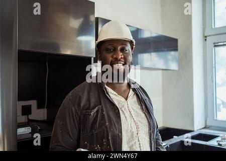 Portrait of smiling male construction manager wearing hardhat in apartment Stock Photo