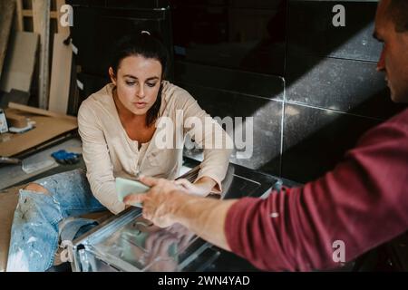 Man discussing and showing mobile phone to woman while renovating home Stock Photo