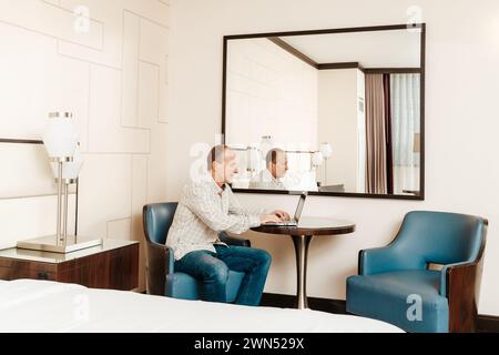 older senior man working on his computer in a hotel room Stock Photo