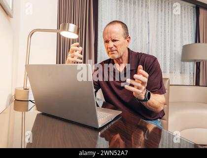 older senior man working on his computer in a hotel room Stock Photo