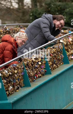 24/03/21   Mollie Edge and Jake Mycock search for and read inscriptions on the padlocks.  The Ôlove lockÕ Weir Bridge over the river Wye in Bakewell. Stock Photo