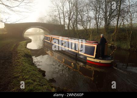 Narrow boat passing under Newton Bridge (no. 164) over the Leeds-Liverpool canal near Bank Newton, Gargrave, North Yorkshire. Stock Photo