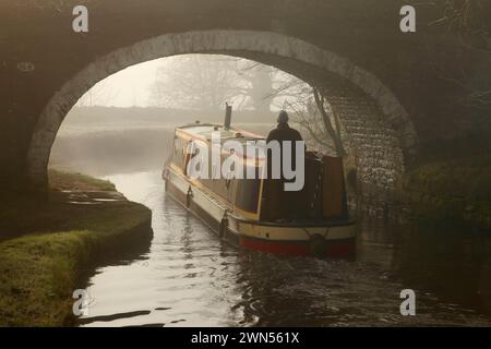 Narrow boat passing under Newton Bridge (no. 164) over the Leeds-Liverpool canal near Bank Newton, Gargrave, North Yorkshire. Stock Photo