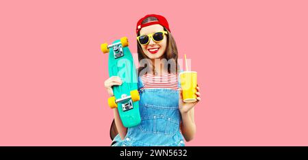 Portrait of happy smiling young woman with skateboard and cup of juice wearing red baseball cap, sunglasses on pink background Stock Photo