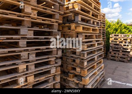 Piles of stacked natural wooden shipping pallets. Outside a big stack with big stack of wooden pallets. Stock Photo
