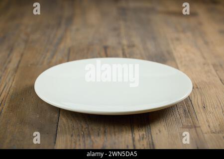 empty white plate on wooden table top, selective focus Stock Photo
