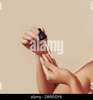 Cropped shot of woman hands holding a pipette against pastel backdrop. Female hands holding a pipette with liquid serum testing consistency with finge Stock Photo
