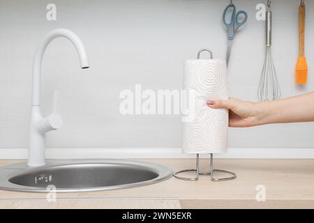 man inserting paper towel into holder in kitchen. paper towel holder. using a paper towel. man putting paper towel on metal holder. Stock Photo