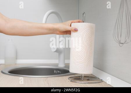man putting paper towel on kitchen counter. kitchen paper towel holder. using a paper towel. Stock Photo