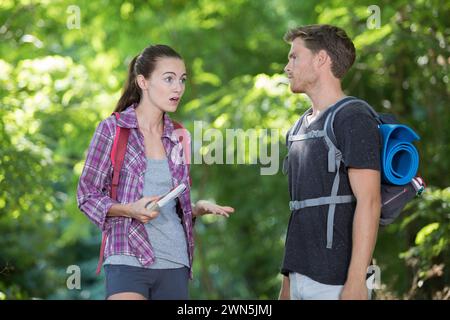 hiking couple with map discussing over direction in forest Stock Photo