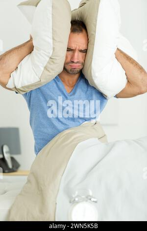 one man trying to sleep covering ears Stock Photo