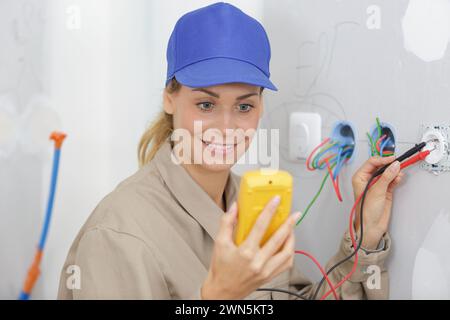 female electrician testing a wall socket Stock Photo