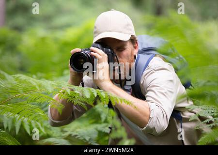 man trekking among trees and taking pictures with dslr camera Stock Photo