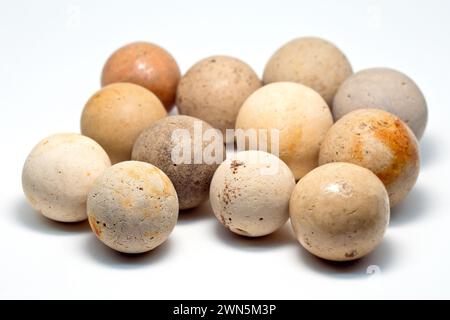 Close up of several old clay pottery marbles, locally known as cheesers, isolated against a white background. Stock Photo