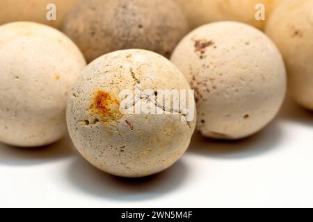 Close up focusing on a single old clay pottery marble out of many, known locally as cheesers, isolated against a white background. Stock Photo