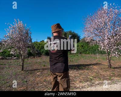 An Israeli stops to take a photo of the blooming fruit trees at the entrance of Beit Guvrin in central Israel on February 29, 2024 as he wears a tee-shirt saying 'We Will dance Again Nova' as some 500 marchers and family members of hostages held in the Gaza Strip march to Jerusalem. Some 500 Israelis are marching today on the second day of their march from the Gaza Strip border communities to Jerusalem calling on the government o come to a decision to free the hostages held since the Hamas murderous spree on October 7, 2023, more than four full months ago. Photo by Jim Hollander/UPI Stock Photo
