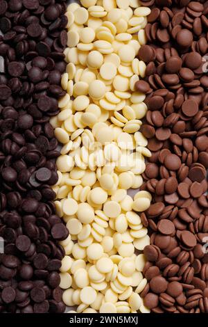 Dark, white and medium dark chocolate drops for making chocolate, candies, cakes as a background. Tempered chocolate confectionery concept. Chocolate Stock Photo