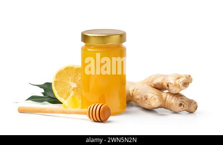 Organic honey in a closed glass transparent jar, a wooden dipper, ginger and a cut lemon with green leaves isolated on a white background. Honey Stock Photo