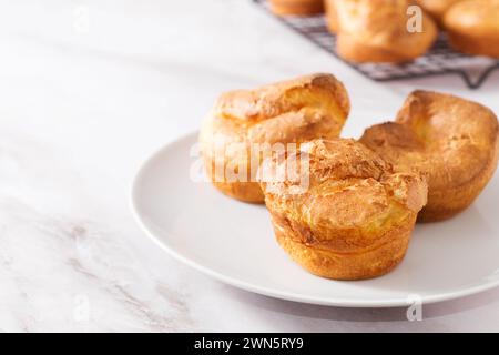 Popovers or Yorkshire pudding on a white plate on a white background, appetizer, breakfast, copy space Stock Photo