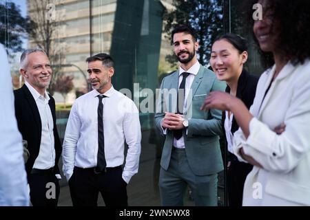 Group of business people standing outside office building, smiling and bonding after work. Stock Photo