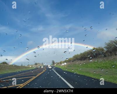 Rain drops on the windshield of the car with blurred rainbow on the background Stock Photo
