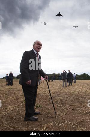 21/08/14  The last surviving British dambuster, George 'Johnny' Johnson (91) watches as two Avro Lancasters and an Avro Vulcan fly over a turf cutting Stock Photo