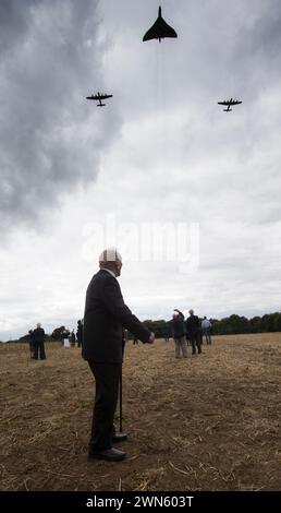 21/08/14  The last surviving British dambuster, George 'Johnny' Johnson (91) watches as two Avro Lancasters and an Avro Vulcan fly over a turf cutting Stock Photo
