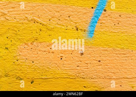 Macro close-up of a spray painted bright yellow and orange wall with turquoise stripe. Abstract full frame textured grunge graffiti background with co Stock Photo