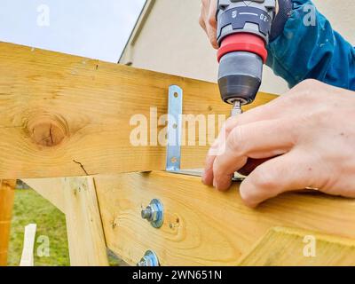 Worker using drill working on construction of wood frame house, gazebo Stock Photo