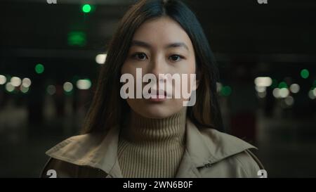 Close up portrait pensive serious Asian chinese ethnic woman young girl businesswoman female in dark parking city unhappy customer car owner client Stock Photo