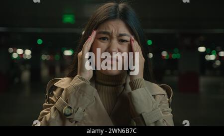 Asian chinese korean woman unhealthy girl in parking japanese female suffer from headache migraine pain covid-19 symptom high blood pressure message Stock Photo