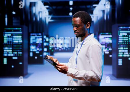 Expert preparing server farm recovery plan monitoring data center energy consumption across components, making sure sensors are functioning optimally, doing routine disk checks Stock Photo