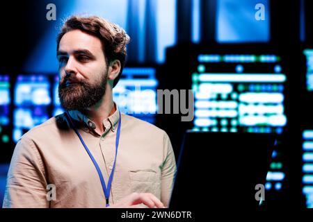 IT Specialist looking at operational servers in computer network security data center. Mainframes providing processing and memory resources needed for computational operations Stock Photo