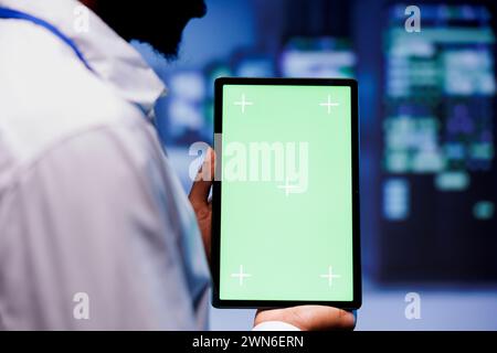 Manager inspecting server racks hosting websites and delivering web content to clients over the internet. Professional using green screen tablet to take note of critical systems, looking for issues Stock Photo
