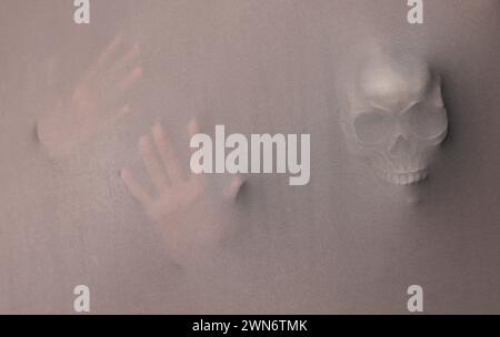 Silhouette of creepy ghost with skull behind grey cloth Stock Photo