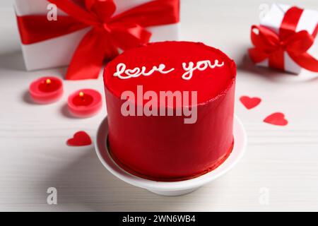 Bento cake with text Love You, gift boxes, candles and paper hearts on white wooden table. St. Valentine's day surprise Stock Photo