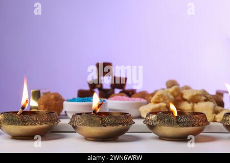 Happy Diwali. Diya lamps on white table against violet background, closeup Stock Photo